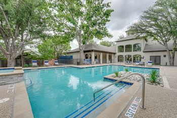 A large swimming pool surrounded by trees and a building in the background.